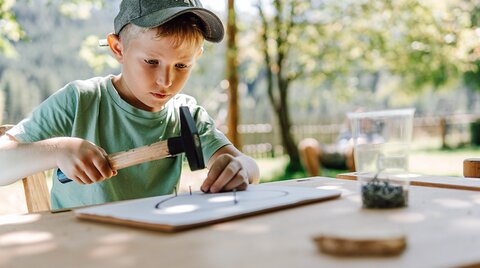 Kind beim Hämmern in der Kinderbetreuung