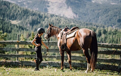 Kind hält Pferd am Zügel vor Bergkulisse
