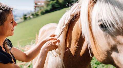 Reitlehrerin Lissy beim Flechten einer Pferdemähne