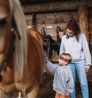 Kind bei der Pferdepflege im Stall