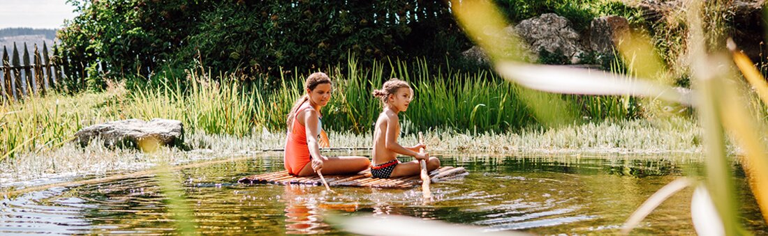 Kinder auf Floß im Schwimmteich