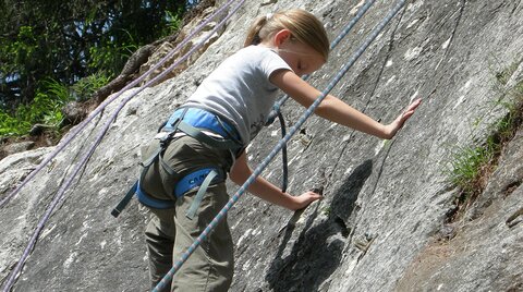 Kind beim Klettern auf einem Fels