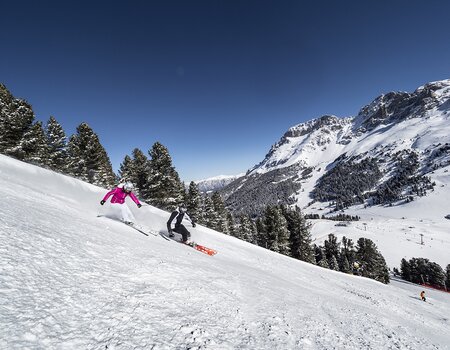 Zwei Skifahrer beim Skifahren auf der Piste